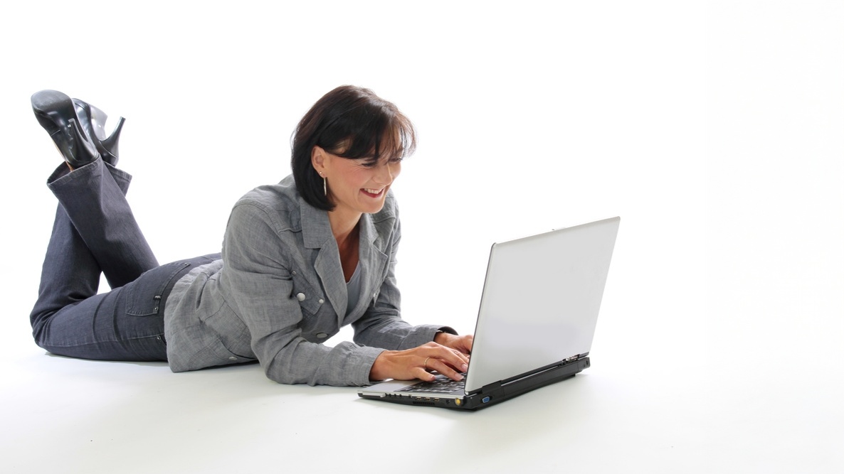 Une professionnelle consulte son ordinateur portable en souriant